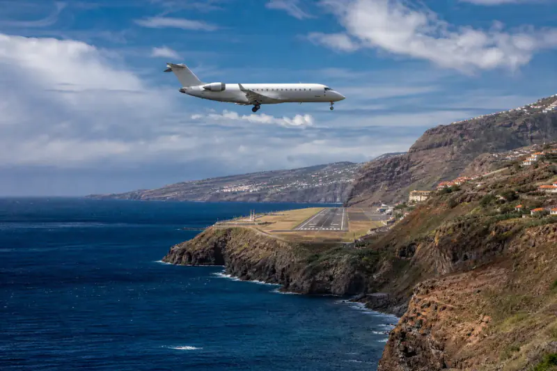 Avião regional em aproximação à pista da Madeira entre o oceano e a falésia
